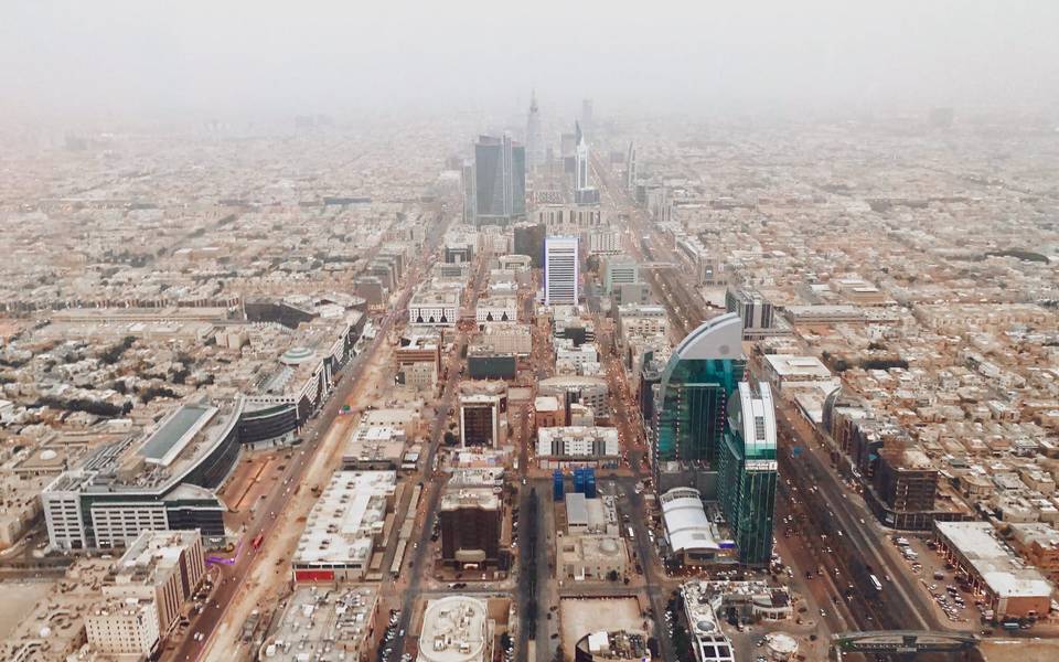 منظر جوي لشارع رئيسي في الرياض تمتد على جانبيه المباني تحت أفق مغبر قليلاً