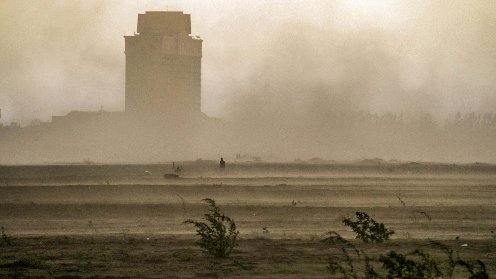 عاصفة ترابية تحجب الأفق فوق أرض صحراوية مفتوحة